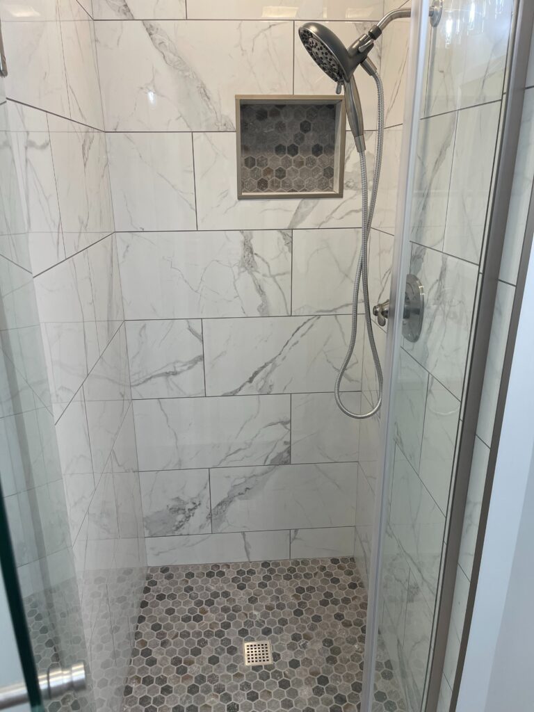 Our team of expert contractors recently completed a stunning renovation that showcases new wall tiles, a sleek vanity, and groutless showers.